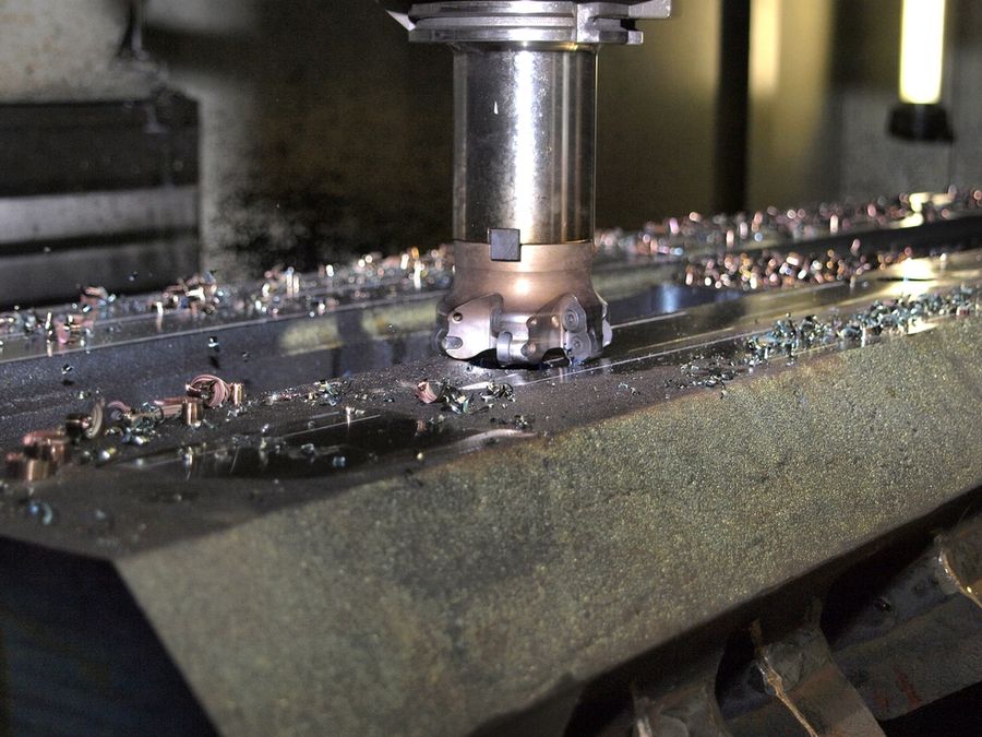 CNC face mill cutting a steel plate, with metal chips on the table