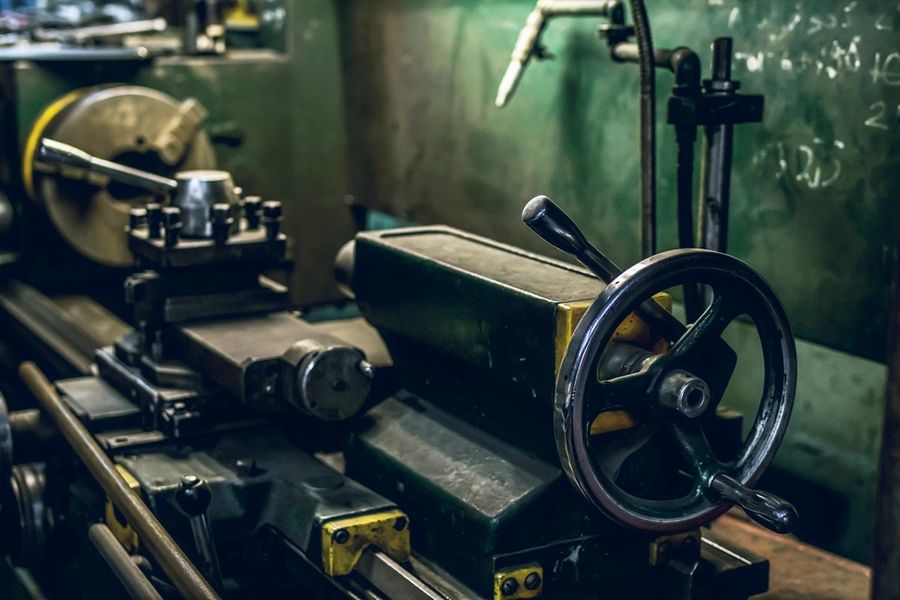 Manual lathe carriage and handwheel in a machine shop